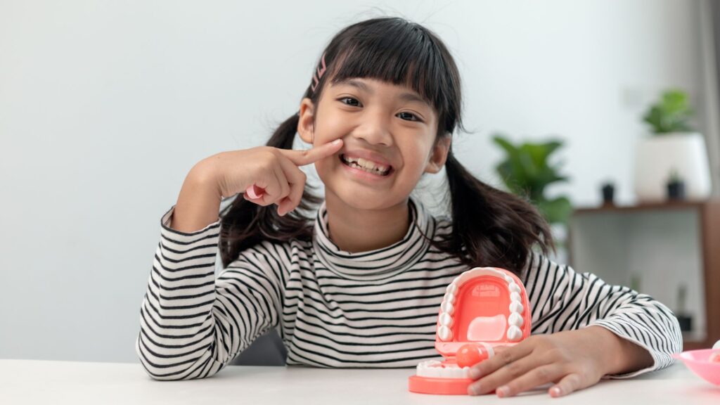 girl smiling with tooth model